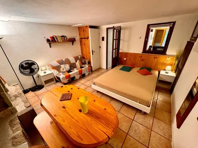 a room with a bed and a table and a couch at Casa Jeannot typique Corse en pierre, UNIQUEMENT DE SAMEDI EN SAMEDI , 2 pers, f2, 35 m2, jardin 60m2 vue montagne, parking in Monacia-dʼAullène