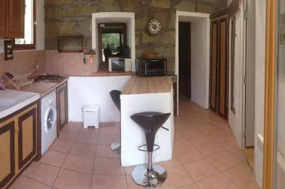 a kitchen with a white island in the middle at Casa Jeannot typique Corse en pierre, UNIQUEMENT DE SAMEDI EN SAMEDI , 2 pers, f2, 35 m2, jardin 60m2 vue montagne, parking in Monacia-dʼAullène