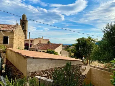 an old building with a clock tower in a village at Casa Jeannot typique Corse en pierre, UNIQUEMENT DE SAMEDI EN SAMEDI , 2 pers, f2, 35 m2, jardin 60m2 vue montagne, parking in Monacia-dʼAullène