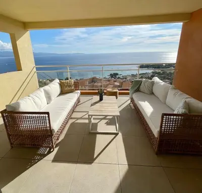 a balcony with two white couches and a table at Paillote Perchée à 180 ° sur la mer in Ajaccio