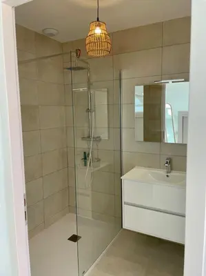 a bathroom with a glass shower and a sink at Paillote Perchée à 180 ° sur la mer in Ajaccio