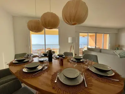 a wooden table with plates and glasses on top of it at Paillote Perchée à 180 ° sur la mer in Ajaccio
