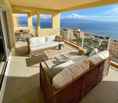 a living room with a couch and a table on a balcony at Paillote Perchée à 180 ° sur la mer in Ajaccio