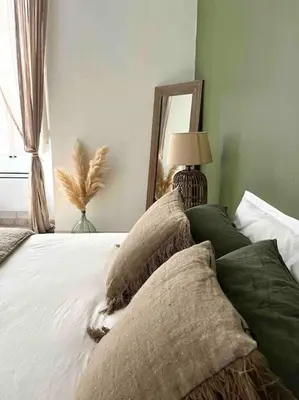 a bedroom with a bed with pillows and a mirror at 83m2 de charme au coeur de la cité impériale in Ajaccio