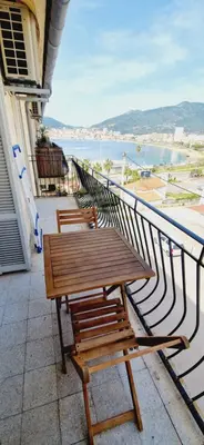 a wooden table and benches on a balcony with a view at Magnifique appartement avec balcon vue mer à l'entrée d'Ajaccio in Ajaccio