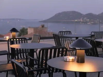 a group of tables and chairs with a view of the water at Hotel Moderne in Porto-Vecchio