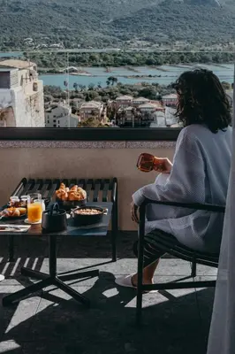 a woman sitting in a chair with a table of food at Hotel Moderne in Porto-Vecchio