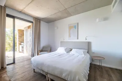 a painting above a bed with two white pillows at Casa Loua in Sainte-Lucie de Porto-Vecchio
