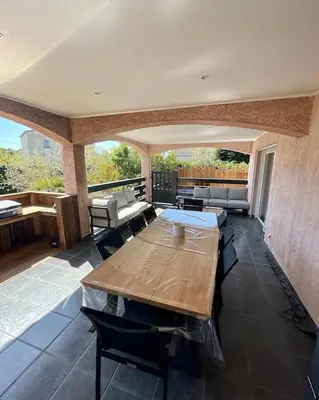 a large patio with a wooden table and chairs at Villa avec piscine entièrement rénovée à 5min de la plage de pinia in Ghisonaccia