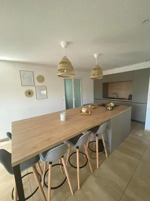 a kitchen with a wooden table and some chairs at Villa avec piscine entièrement rénovée à 5min de la plage de pinia in Ghisonaccia