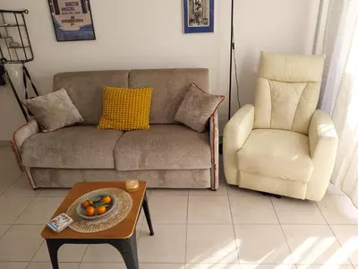 a living room with a couch and a chair and a table at Les villas de Mélody in Santa-Maria-Poggio