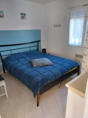a bedroom with a bed with a blue comforter at Les villas de Mélody in Santa-Maria-Poggio