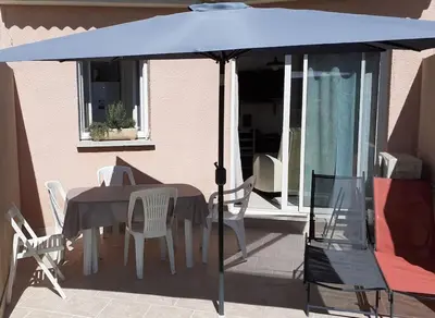 a table and chairs under an umbrella on a patio at Les villas de Mélody in Santa-Maria-Poggio