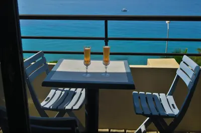 a table with two glasses of wine on a balcony at STUDIO LES CALANQUES in Ajaccio
