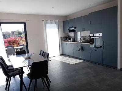 a kitchen with blue cabinets and a table with chairs at côte et mer - appartement haut standing dans villa avec piscine et vue mer in Taglio-Isolaccio