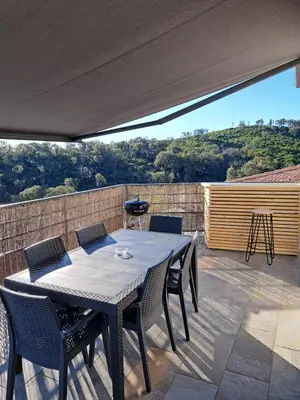 a patio with a table and chairs on a deck at côte et mer - appartement haut standing dans villa avec piscine et vue mer in Taglio-Isolaccio