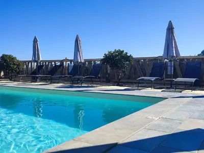 a swimming pool with chairs and umbrellas next to a building at côte et mer - appartement haut standing dans villa avec piscine et vue mer in Taglio-Isolaccio