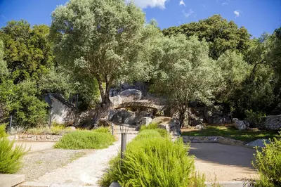 a stone bridge in a park with trees and bushes at Domaine d'Arca - Hugo 06 - 2 pers in Porto-Vecchio