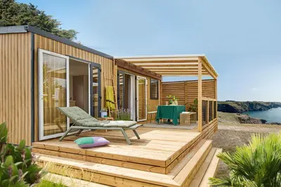 a tiny house with a deck and a table at Camping California in Pinarellu