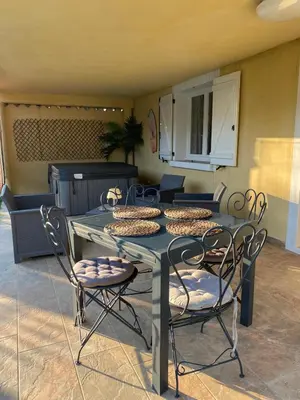 a glass table and chairs in a living room at Agréable rez de jardin avec Piscine et Jacuzzi in Cervione