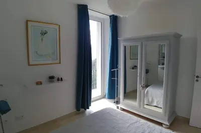 a room with a bedroom with blue curtains and a mirror at CHEZ PERLE à LEVIE, logement entier de type T4 in Levie