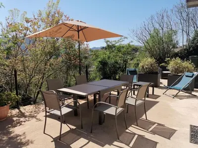 a table and chairs with an umbrella on a patio at CHEZ PERLE à LEVIE, logement entier de type T4 in Levie