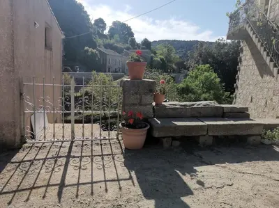 a stone bench sitting next to a fence with flowers at CHEZ PERLE à LEVIE, logement entier de type T4 in Levie