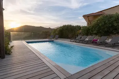 a swimming pool with chairs on a wooden deck at Villa Kallisté piscine chauffée in Serra-di-Ferro