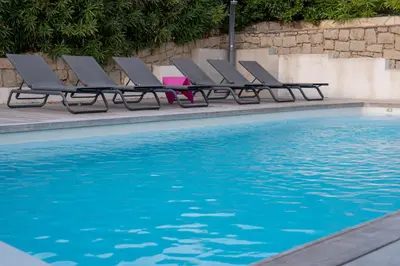 a row of lounge chairs next to a swimming pool at Villa Kallisté piscine chauffée in Serra-di-Ferro