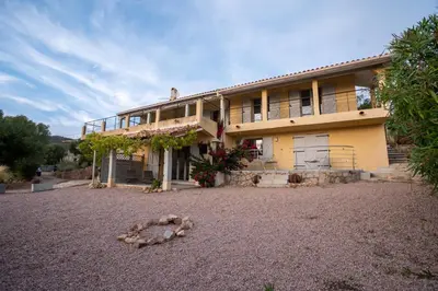 a large yellow house with a gravel yard at Villa Kallisté piscine chauffée in Serra-di-Ferro