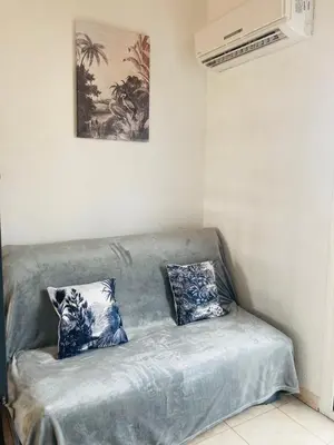 a couch with two blue and white pillows on it at Bel appartement dans résidence avec piscine in Linguizzetta