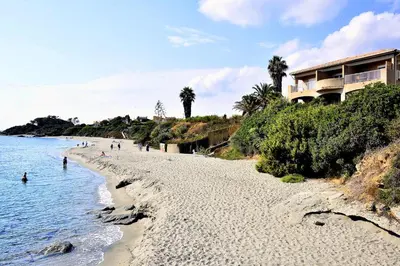 a beach with people in the water and a building at Bel appartement dans résidence avec piscine in Linguizzetta