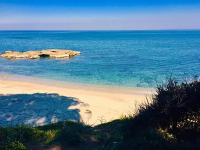 a view of a beach with rocks in the water at Bel appartement dans résidence avec piscine in Linguizzetta
