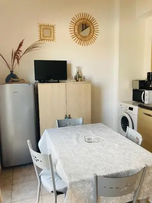 a dining room with a table and a refrigerator at Bel appartement dans résidence avec piscine in Linguizzetta