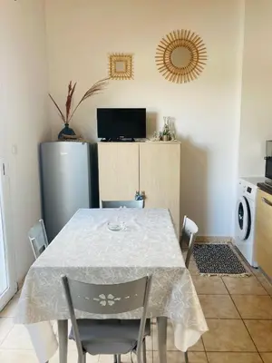 a kitchen with a table with chairs and a refrigerator at Bel appartement dans résidence avec piscine in Linguizzetta