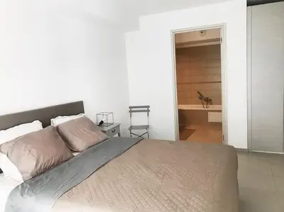 a bedroom with a large bed and a bathroom at SUPERBE APPARTEMENT SUR PLAGE VUE PARADISIAQUE PIEDS DANS L'EAU in Propriano