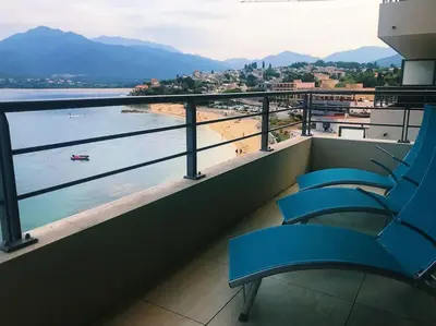 a balcony with blue chairs and a view of a beach at SUPERBE APPARTEMENT SUR PLAGE VUE PARADISIAQUE PIEDS DANS L'EAU in Propriano