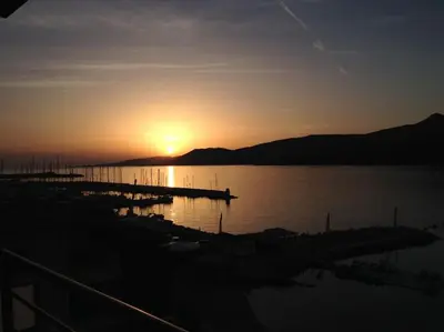 a sunset over a body of water with a dock at SUPERBE APPARTEMENT SUR PLAGE VUE PARADISIAQUE PIEDS DANS L'EAU in Propriano