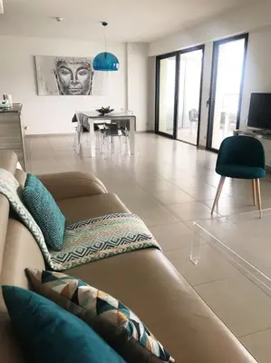 a living room with a couch and a table at SUPERBE APPARTEMENT SUR PLAGE VUE PARADISIAQUE PIEDS DANS L'EAU in Propriano