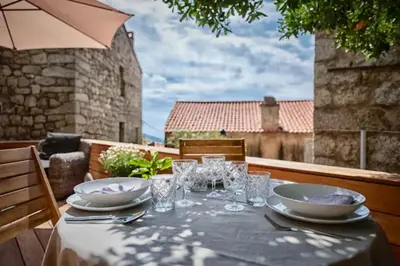 a table with plates and glasses and an umbrella at Maison Madamicella in Fozzano