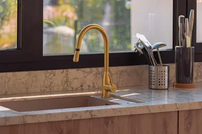 a kitchen sink with a gold faucet next to a window at Villa Blue Pearl 10 pers piscine chauffée 10 minutes plage à pieds in Sainte-Lucie de Porto-Vecchio