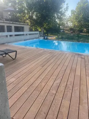 a wooden deck with a swimming pool in front of a building at T3 dans charmante propriété in Borgo