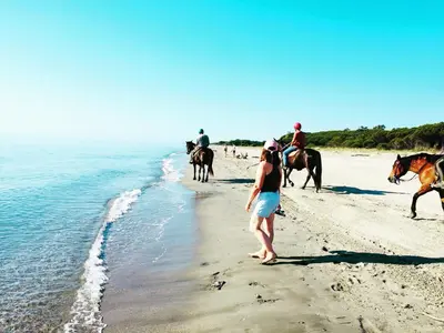 a group of people riding horses on the beach at Beach house à Marina di Sorbo …Corse in Sorbo-Ocagnano