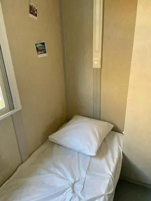 a bed in a small room with a white pillow at Chalet climatisé avec patio en Haute Corse 5 couchages in Camp du Cap Sud