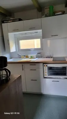 a kitchen with white cabinets and a sink and a window at Chalet climatisé avec patio en Haute Corse 5 couchages in Camp du Cap Sud