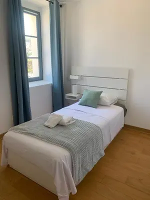 a bedroom with a white bed with a window at Les Hauts du Port-Appartement neuf sur le port in Bonifacio