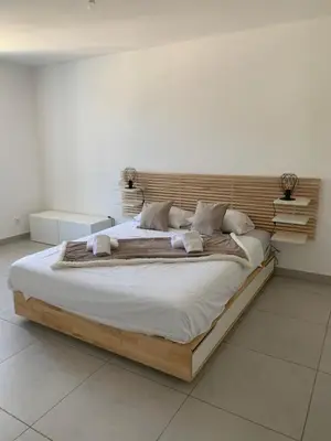 a large bed with a wooden headboard in a bedroom at Les Hauts du Port-Appartement neuf sur le port in Bonifacio