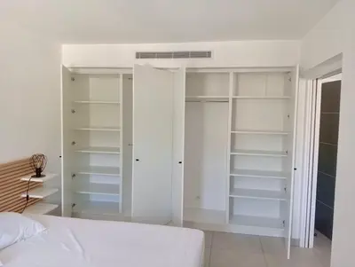 a white bedroom with white shelves and a bed at Les Hauts du Port-Appartement neuf sur le port in Bonifacio