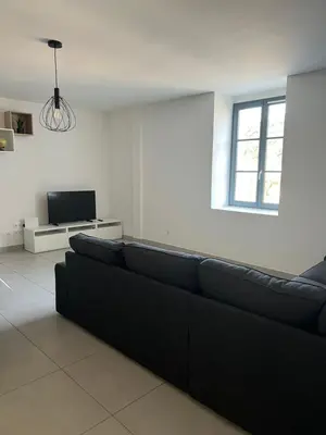 a living room with a black couch and a tv at Les Hauts du Port-Appartement neuf sur le port in Bonifacio