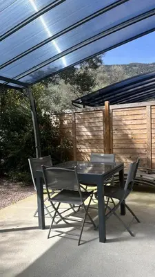 a black table and two chairs under an umbrella at N8 Maison T2 climatisé in Ajaccio